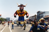 Marchers pull costumed inflatable bull in Pride parade, 1996