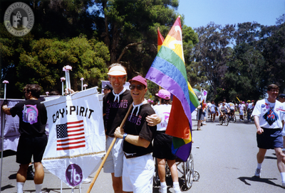 Pride parade marchers hold flags, including 1976 Pride theme, 1992