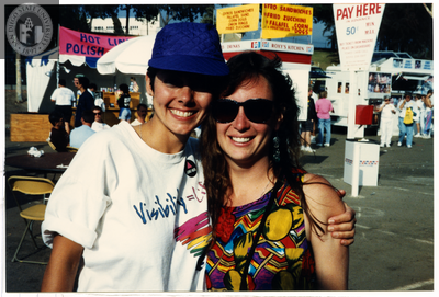People hugging in front of food stands at Pride festival, 1999