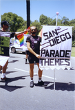 Volunteer holds "San Diego Parade Themes" sign in Pride parade, 1992