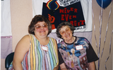 Elsa and Muriel in front of  banner at Pride festival, 1996