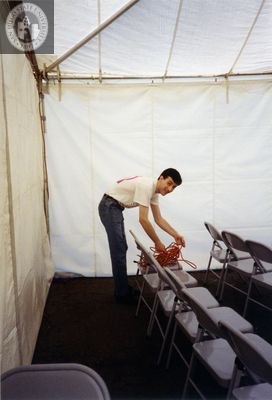Volunteer sets up electrical cords in Lesbian and Gay Archives tent, 1992