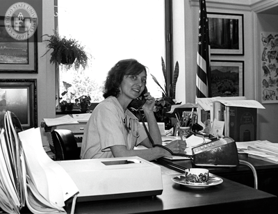 Unidentified woman at desk using telephone