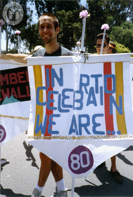 Pride parade marcher holds flag with 1980 Pride theme, 1992