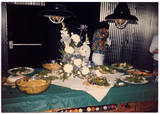 Food and flowers set up on pool table with person eating in background