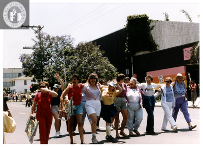 Women smile and wave with their arms around each other in Pride parade, 1988