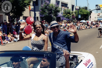 Couple riding on back of Bob Baker car at Pride parade, 1999