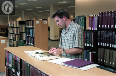 Student looks at book in library, 1998