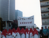 "We've had enough!" sign with people in red veils wearing white