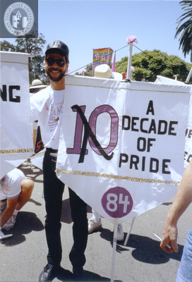 Volunteer holding flag with 1984 Pride theme in Pride parade, 1992