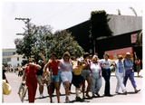 Women smile and wave with their arms around each other in Pride parade, 1988