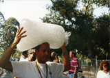 Person carrying large ice bag on their head outside Pride grounds