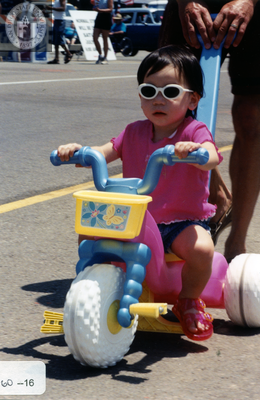 Child in sunglasses on plastic tricycle in Pride parade, 2000