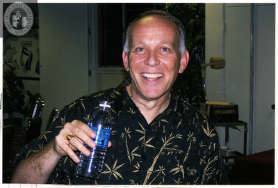 Person smiling and holding a water bottle at Pride festival, 2006