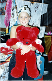 Child holding red stuffed bear at For the Children, 1996