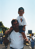 Child being carried on shoulders by male at For the Children, 1996