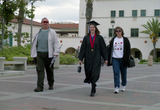 A graduating senior walks with her parents on Graduation Day, 1999