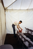 Volunteer sets up electrical cords in Lesbian and Gay Archives tent, 1992