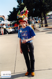 Staff member with feather-decorated hat at Pride rally, 1999