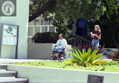Man in wheelchair and woman at directional sign, 1996