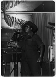 Al Bess performing on stage in hat and sunglasses