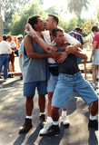 Two men kissing while wrestling third male at Pride parade, 1996