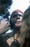 Two people paint someone's face and chest at the San Diego Gay-In, 1970