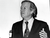 Lionel Van Deerlin speaks in close up at a microphone, 1980