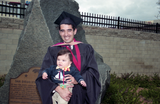 Advanced-degree graduate in cap and gown, with baby, 1999