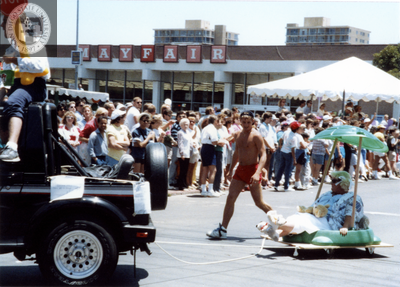 Person on mini float being pulled by a pickup truck in Pride parade, 1988
