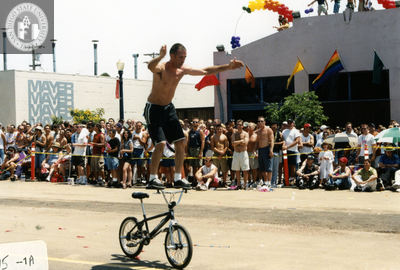 Person standing on bicycle handlebars in Pride parade, 2000