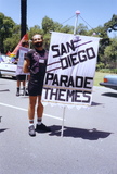 Volunteer holds "San Diego Parade Themes" sign in Pride parade, 1992