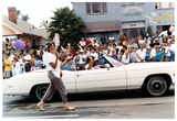 Person claps and walks next to a convertible in Pride parade, 1998