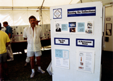 Person standing next to LGHSSD display at Pride festival, 1993