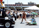Person on mini float being pulled by a pickup truck in Pride parade, 1988