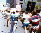 Marchers with signs and flag in Pride parade