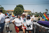Cheli Mohamed standing with two individuals next to float at Pride parade, 1996