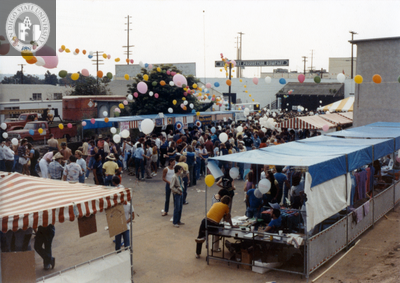 Sign up or vendor booths with balloons strung above at Pride festival, 1982