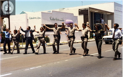 Law enforcement officials marching with raised arms in Pride Parade, 1992